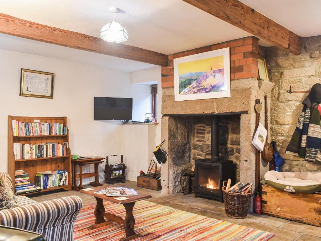 a living room with a stone fireplace and a tv at Beeton Cottage Todmorden in Eastwood