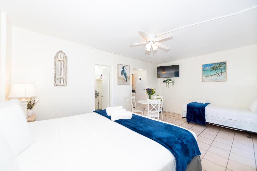 a white bedroom with two beds and a ceiling fan at Tropic Isle Hotel & Apartment in Hollywood