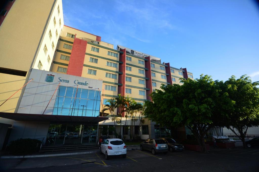 un grand bâtiment avec des voitures garées dans un parking dans l'établissement Hotel Serra Grande - SERRA - ES, à Serra