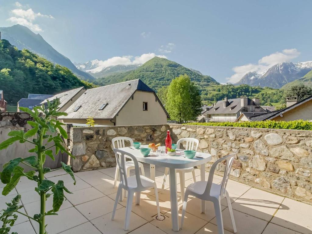 une table et des chaises blanches sur une terrasse avec des montagnes dans l'établissement Appartement Esquièze-Sère, 3 pièces, 6 personnes - FR-1-402-93, à Esquièze - Sère