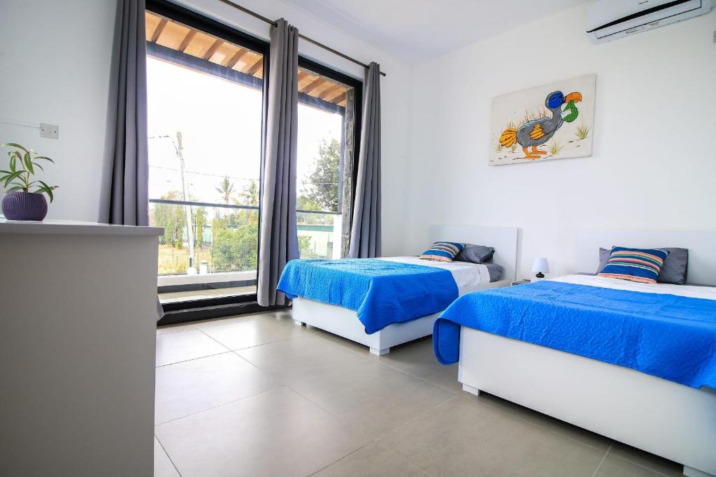 a bedroom with two beds and a large window at Villa Grain de café, 3 chambres piscine accès plage in Trou aux Biches