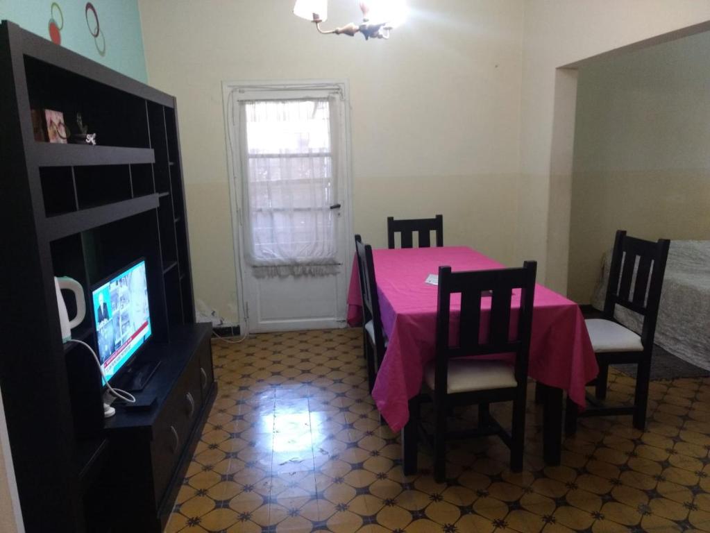 comedor con mesa y sillas rosas y TV en Departamentos Necochea en Godoy Cruz