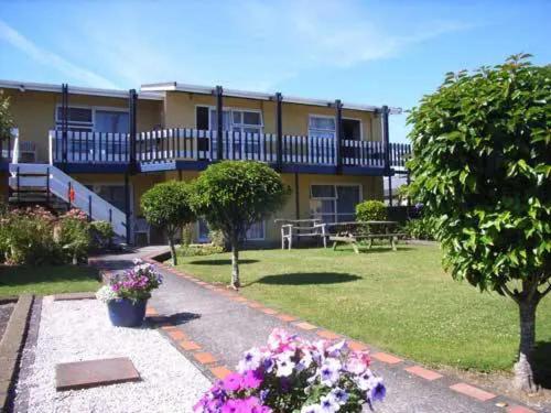 a building with a yard with flowers in front of it at Parkside Motel and Apartments in New Plymouth