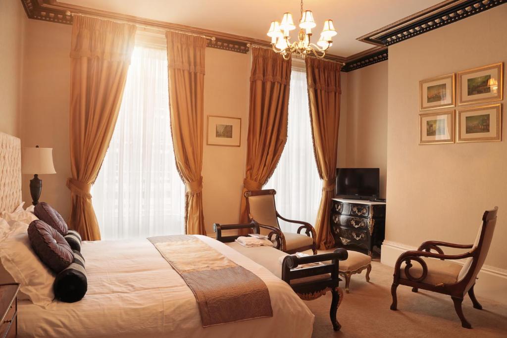 a bedroom with a bed and two chairs and a television at The Georgian Town House Hotel in Liverpool