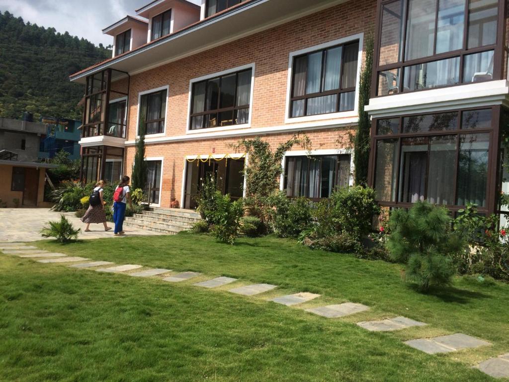 dwoje ludzi przechodzi przed budynkiem w obiekcie Drala Resort Nepal w Katmandu