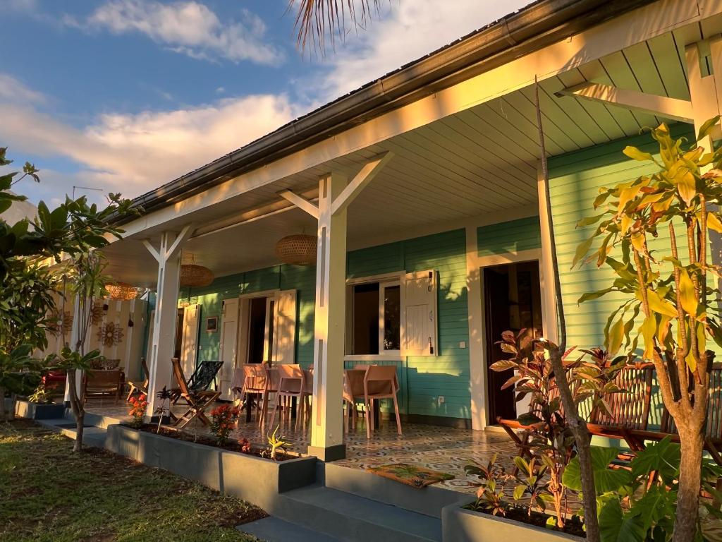 une maison verte avec une terrasse couverte dotée d'une table et de chaises dans l'établissement JOLIE CREOLE- Villa sur le lagon, à La Saline les Bains