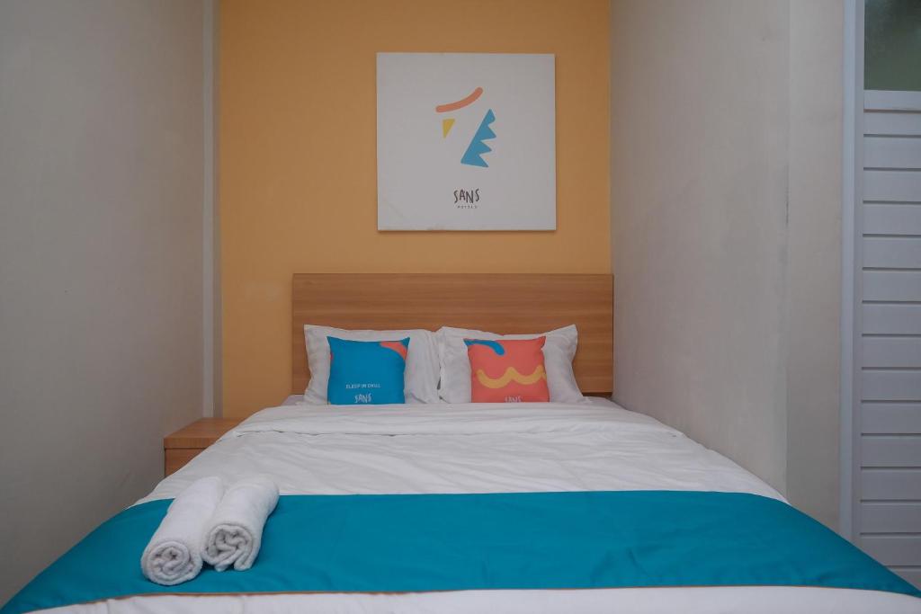 三寶壟的住宿－Sans Hotel Tiga Putri Semarang by RedDoorz，一间卧室配有一张带色彩缤纷枕头的大床