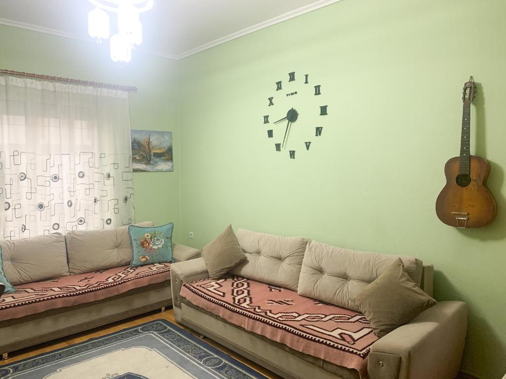 Sala de estar con sofá y guitarra en la pared en Korca Central Flat, en Korçë