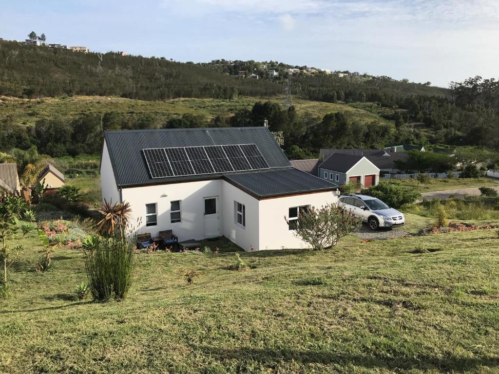 a white house with solar panels on the roof at Stylish Country Cottage, Solar panelled in Knysna in Knysna