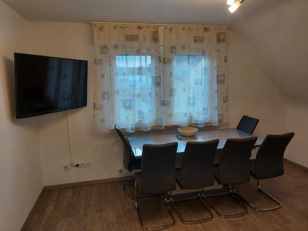 uma sala de jantar com uma mesa e cadeiras e uma televisão em Apartment Popp em Erzhausen