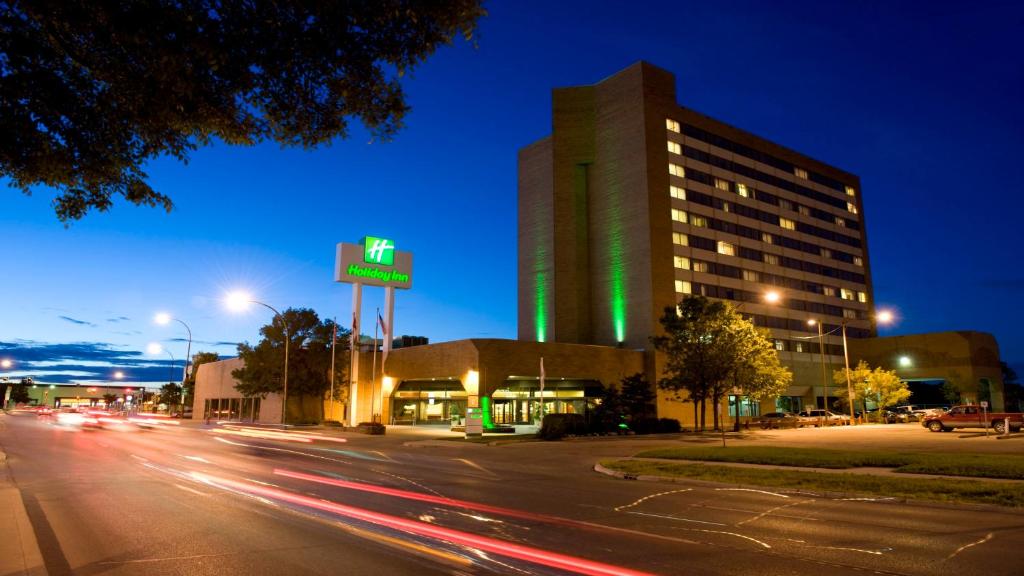 um edifício numa rua da cidade à noite com carros em Holiday Inn Winnipeg-South, an IHG Hotel em Winnipeg