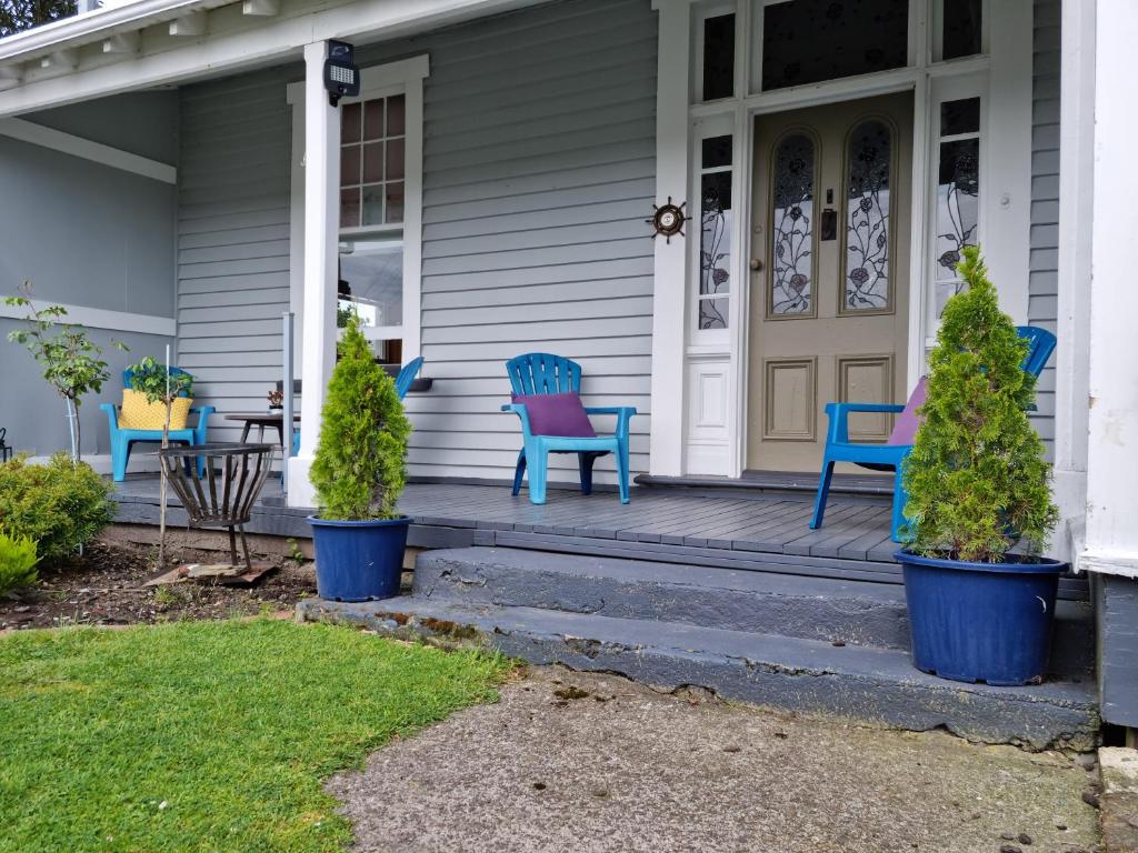 un porche con sillas azules y árboles en una casa en Homestay On Queen en Westport