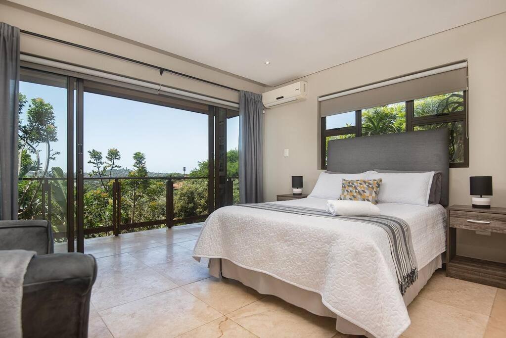 a bedroom with a large bed and a balcony at 9 On Crystal Cove 5 Bedroom Townhouse in Zimbali in Ballito