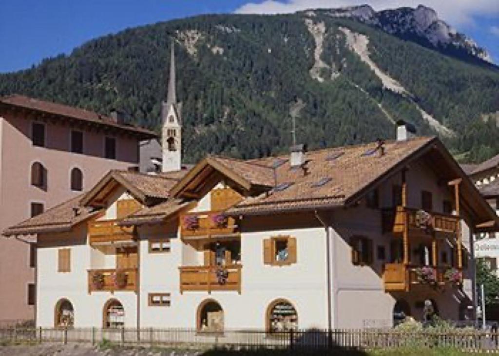 ein großes Gebäude mit einer Kirche und einem Berg in der Unterkunft Residence Margherita in Moena