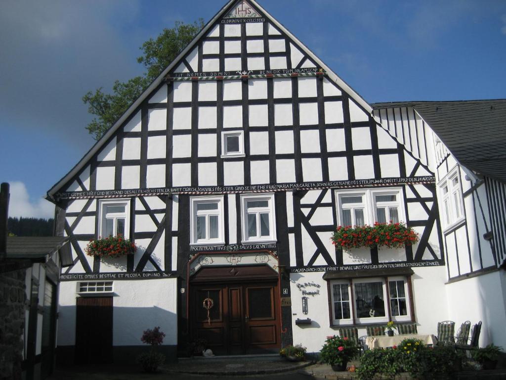 a black and white building with flowers in front of it at Pension Hampel in Schmallenberg
