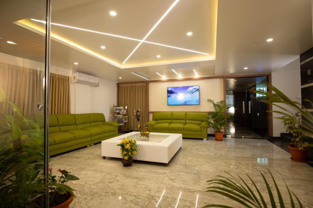 a living room with green couches and a couch at Villa Grand Hotel Near Kempegowda International Airport in Bangalore