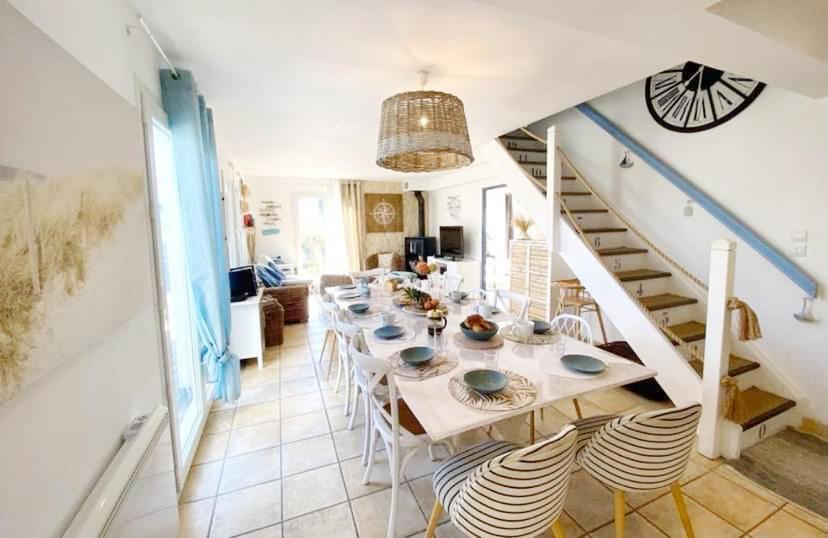 una sala da pranzo con un lungo tavolo e una scala di Les gites du bord de mer a Plouarzel