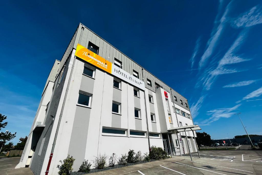 un edificio blanco con un letrero amarillo en el lateral en The Originals Access, Hôtel les Iris, Berck-sur-Mer en Berck-sur-Mer