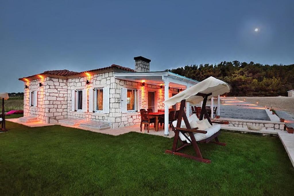 a small stone house with a table and a chair at Lovely Villa with Backyard in Bozcaada near Beach in Canakkale