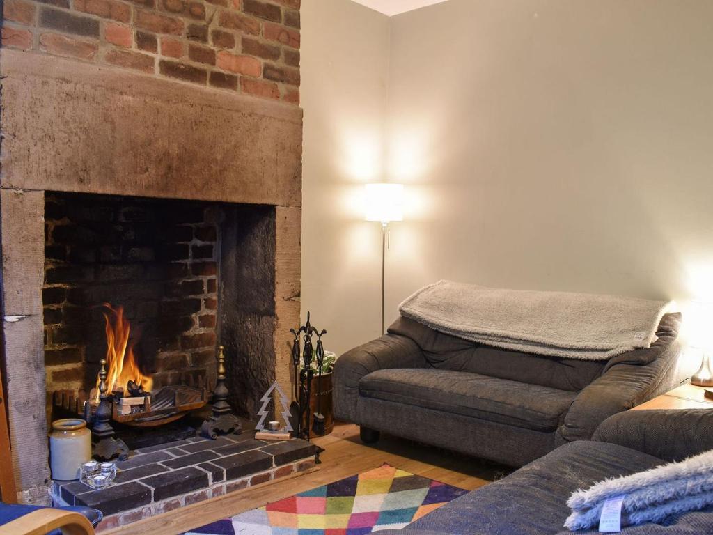 a living room with a couch and a fireplace at Vine Cottage in Crich