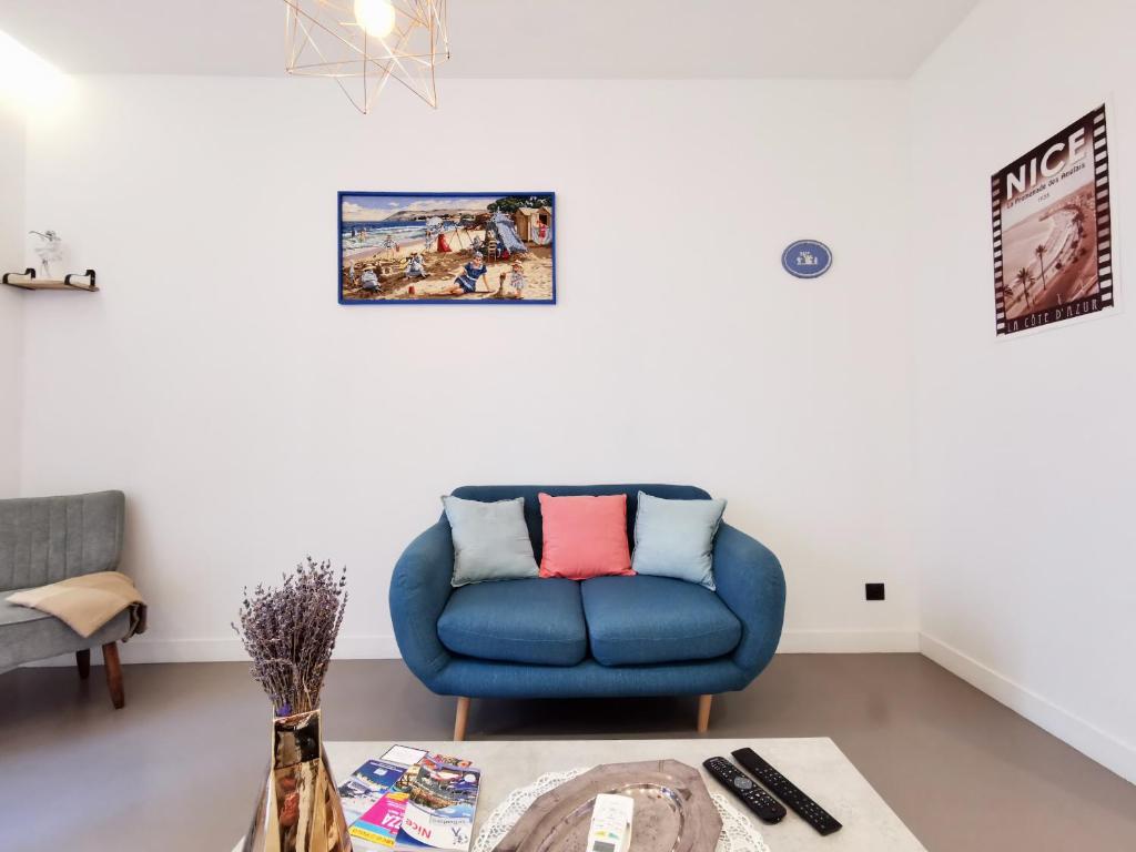 a living room with a blue chair and a table at Le PETIT BALCON by Booking Guys in Nice