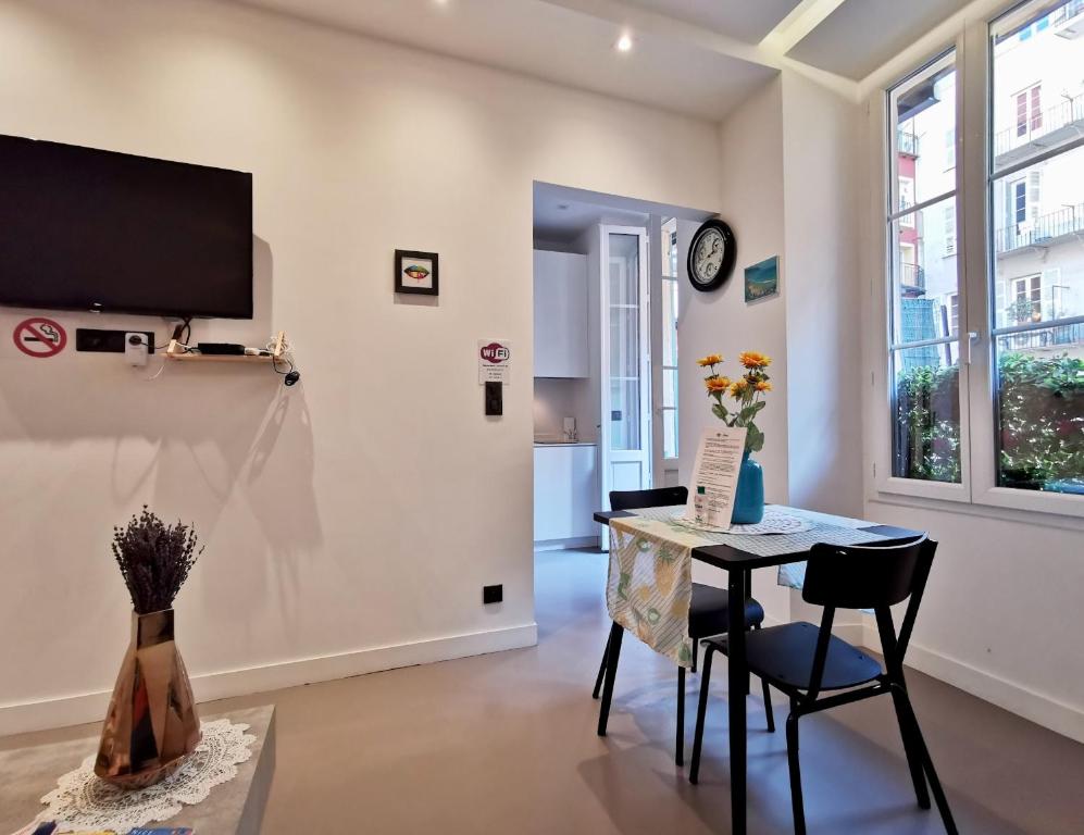 a living room with a table and chairs and a tv at Le PETIT BALCON by Booking Guys in Nice