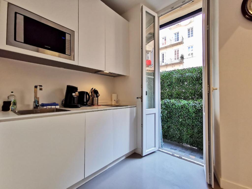 a kitchen with white cabinets and a sliding glass door at Le PETIT BALCON by Booking Guys in Nice