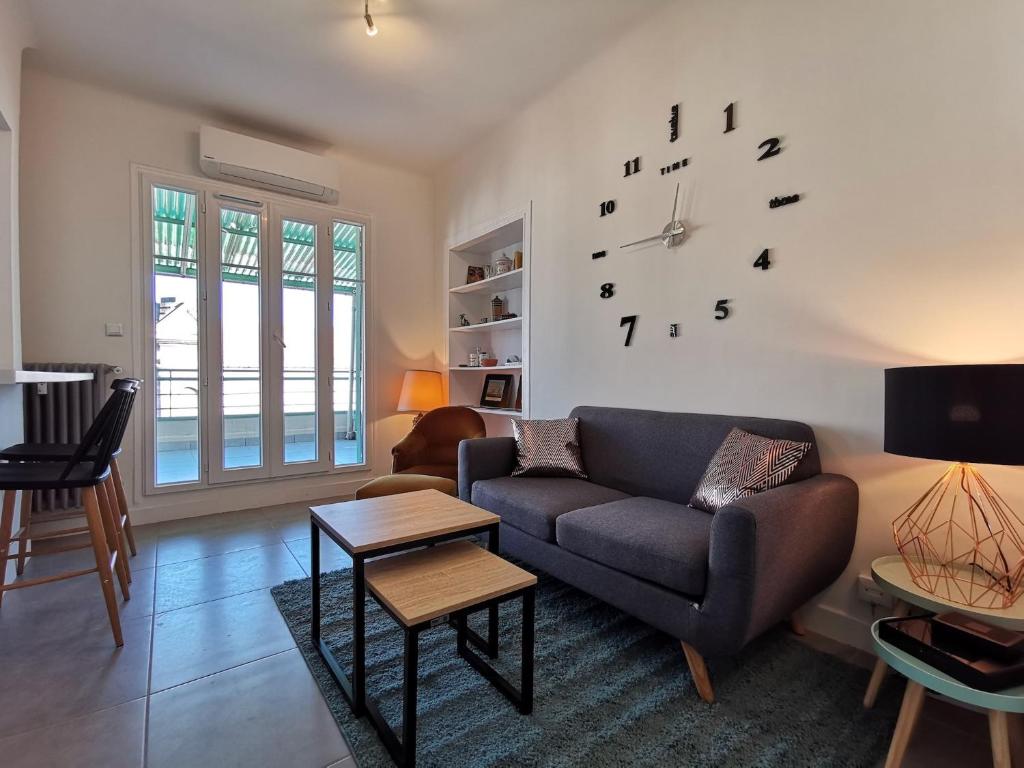 un salon avec un canapé et une horloge au mur dans l'établissement Le SAINT PIERRE, à Nice