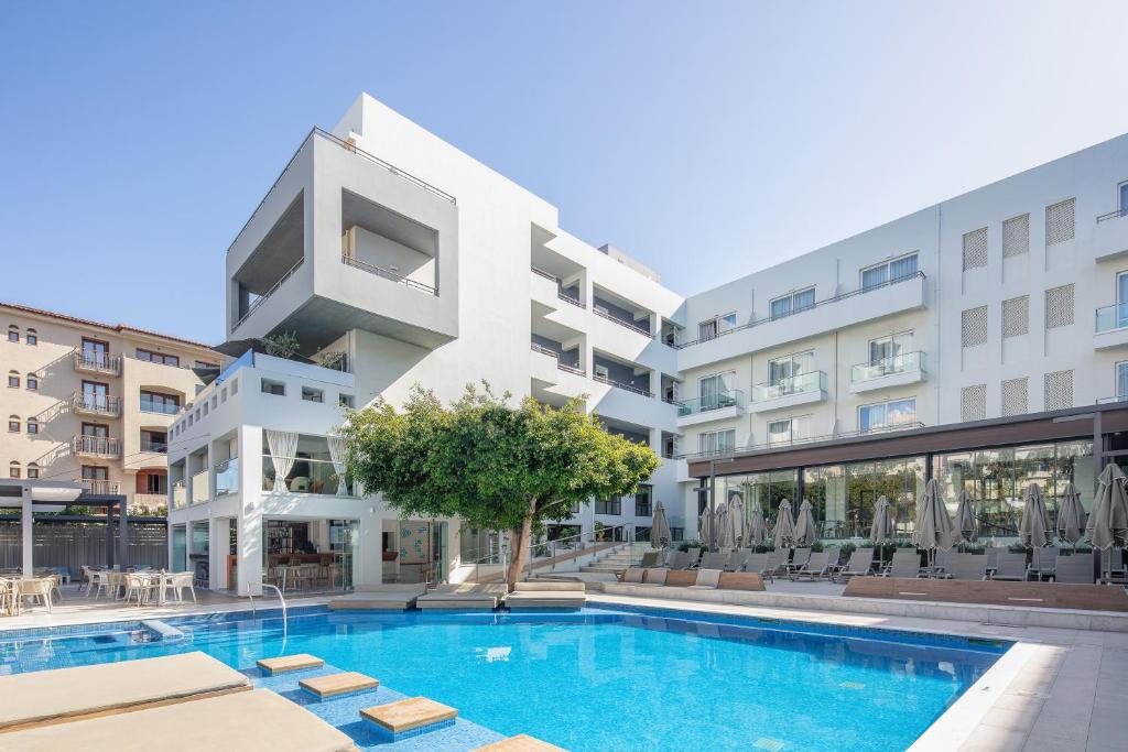 ein Apartmenthaus mit einem Pool vor einem Gebäude in der Unterkunft Atrium Ambiance Hotel in Rethymno