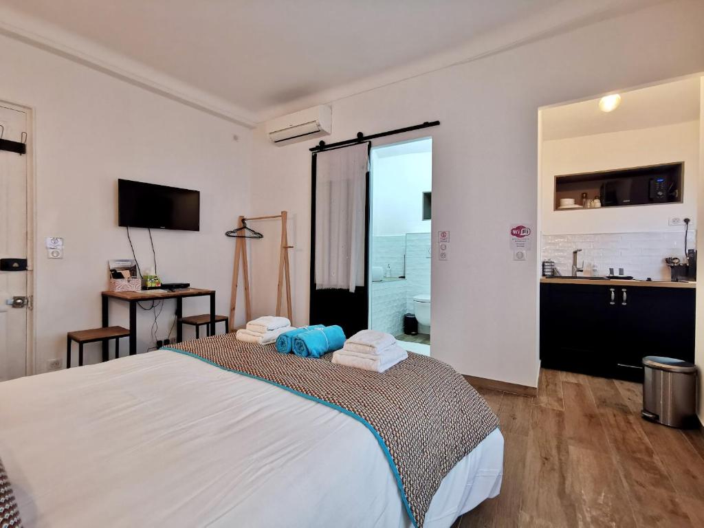 une chambre avec un grand lit blanc et une cuisine dans l'établissement STUDIO PETIT OPERA, à Nice