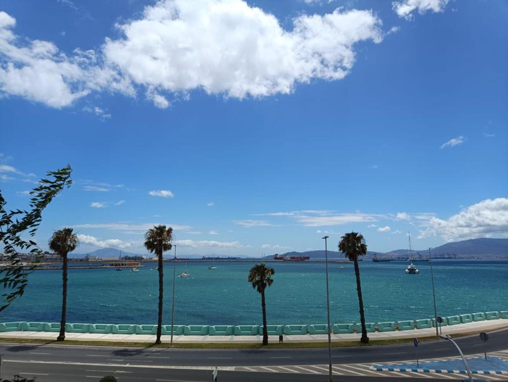 una calle con palmeras frente a un cuerpo de agua en Vistas a 3 Países y 2 Continentes 1º linea de Playa a 5 minutos de Gibraltar en La Línea de la Concepción