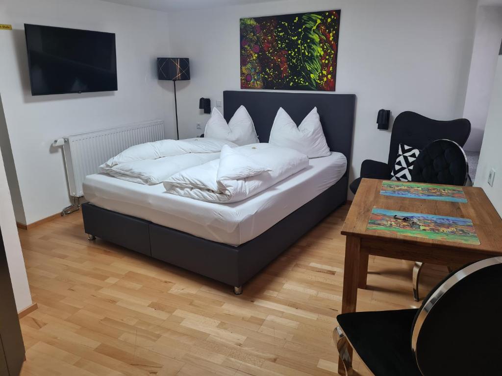 Schlafzimmer mit einem Bett mit weißen Kissen und einem Tisch in der Unterkunft Gästeapartment Pfaff in Rottweil