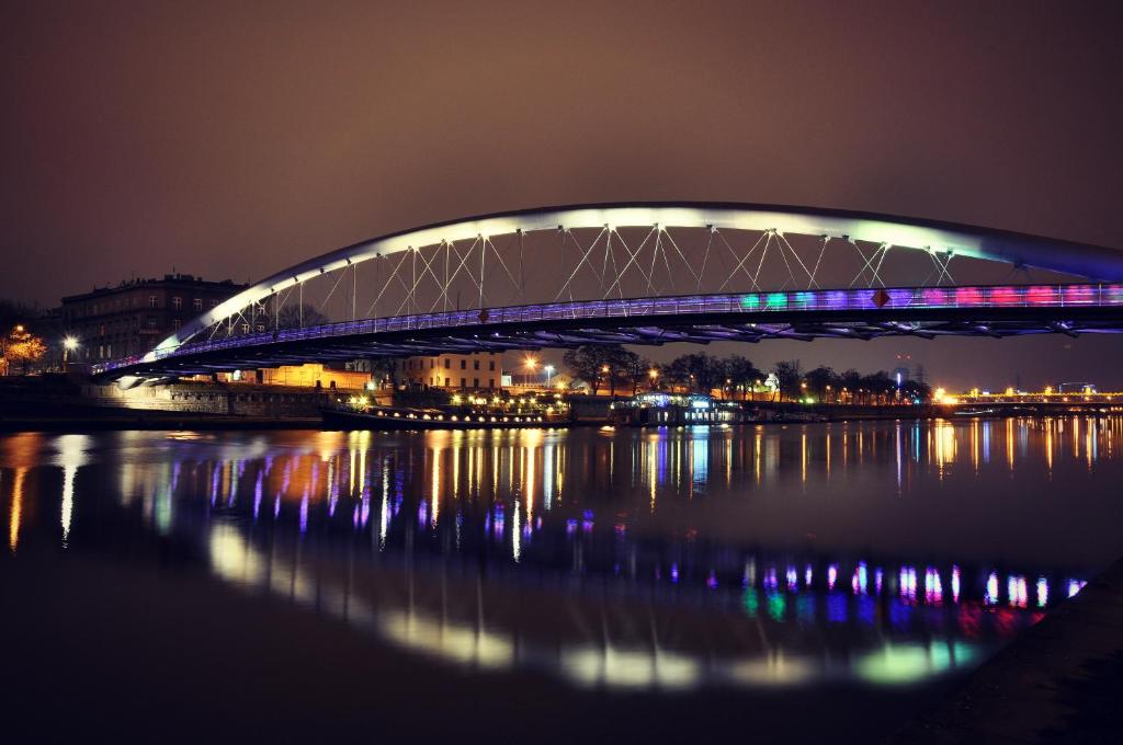a bridge over the water at night at K12 Apartments in Krakow