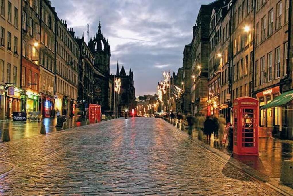 an empty city street at night with a red phone booth at *Amazing Location!*In heart of the City. 2BR & Cot in Edinburgh