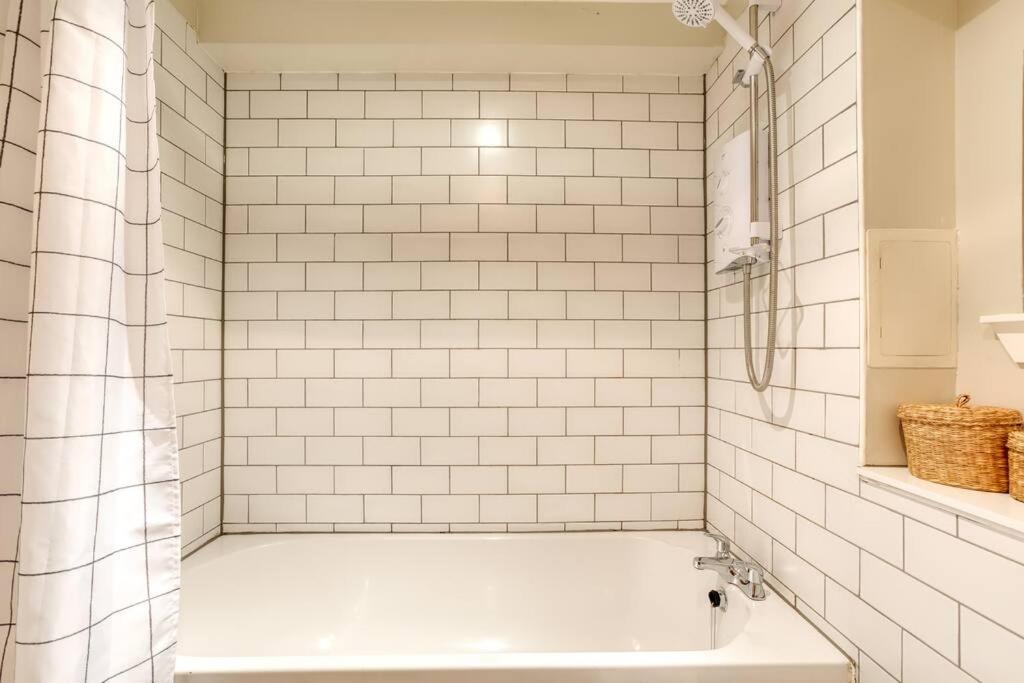 a white tiled bathroom with a tub and a shower at *Amazing Location!*In heart of the City. 2BR & Cot in Edinburgh