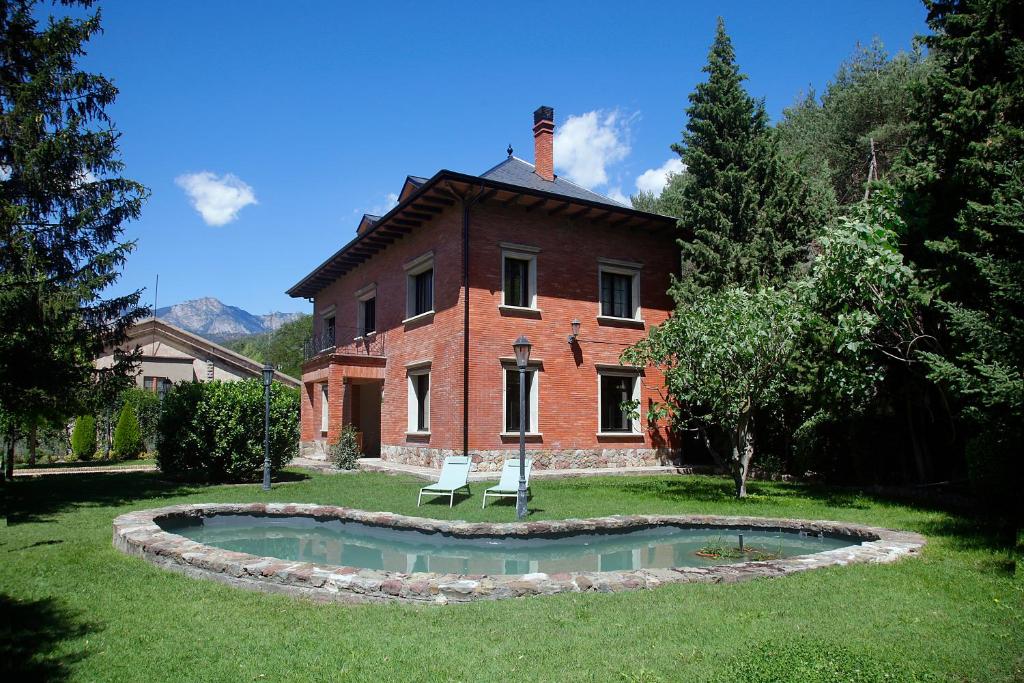 a brick house with a pond in front of it at La Torre de Guardiola in Guardiola de Berguedà