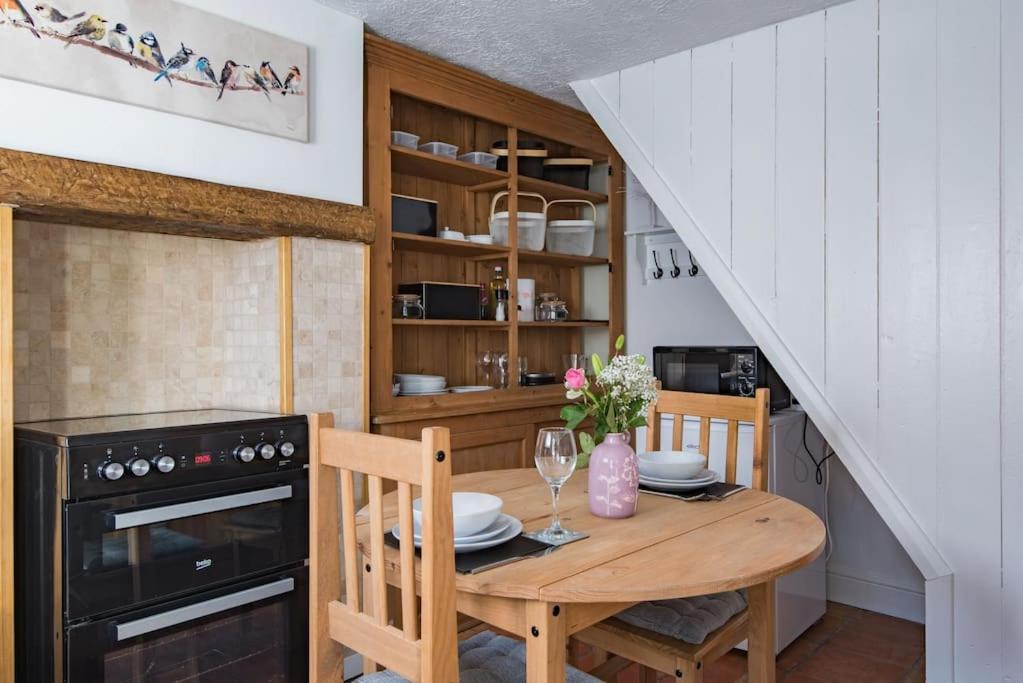 uma cozinha com uma mesa de madeira e um forno preto em Brook Cottage em Temple Ewell