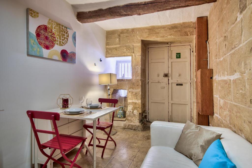 uma sala de estar com uma mesa e um sofá branco em Augustinian em Valletta