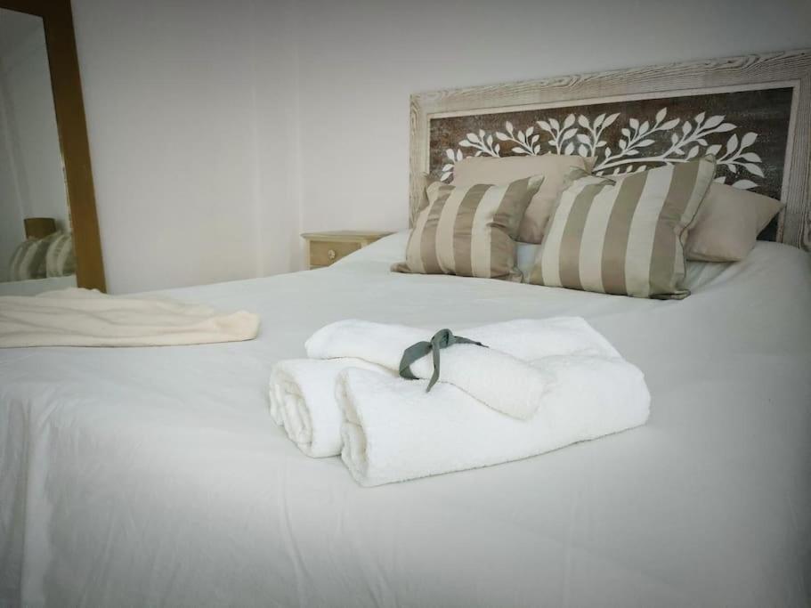 uma cama branca com toalhas por cima em Piso 1km de Salinas em Raíces