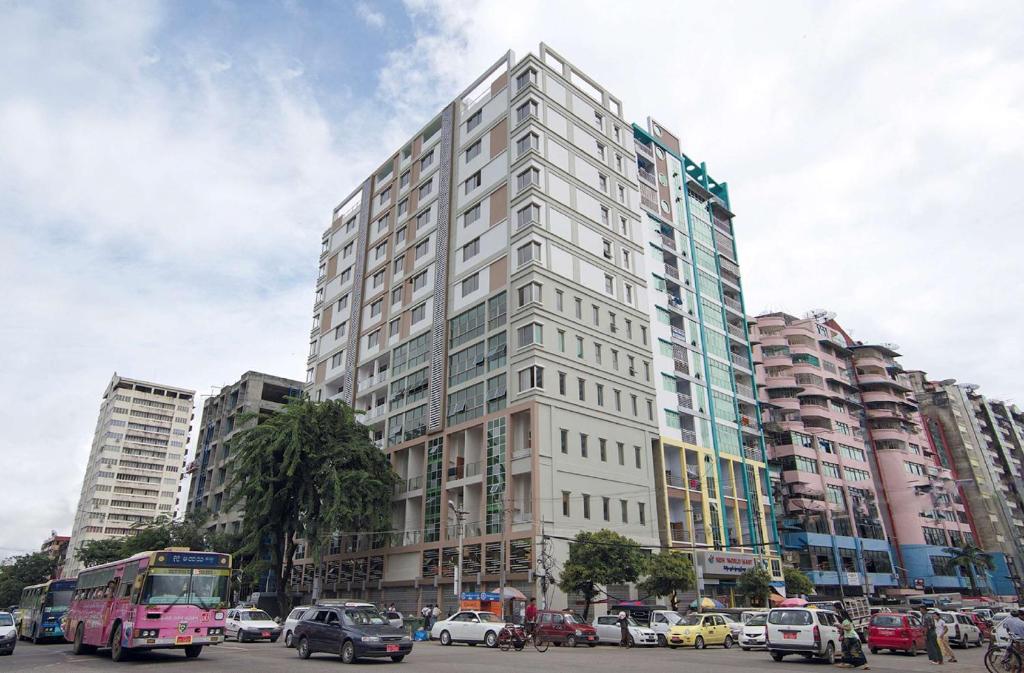 Best Western Chinatown Hotel في يانغون: مبنى أبيض طويل في مدينة بها سيارات