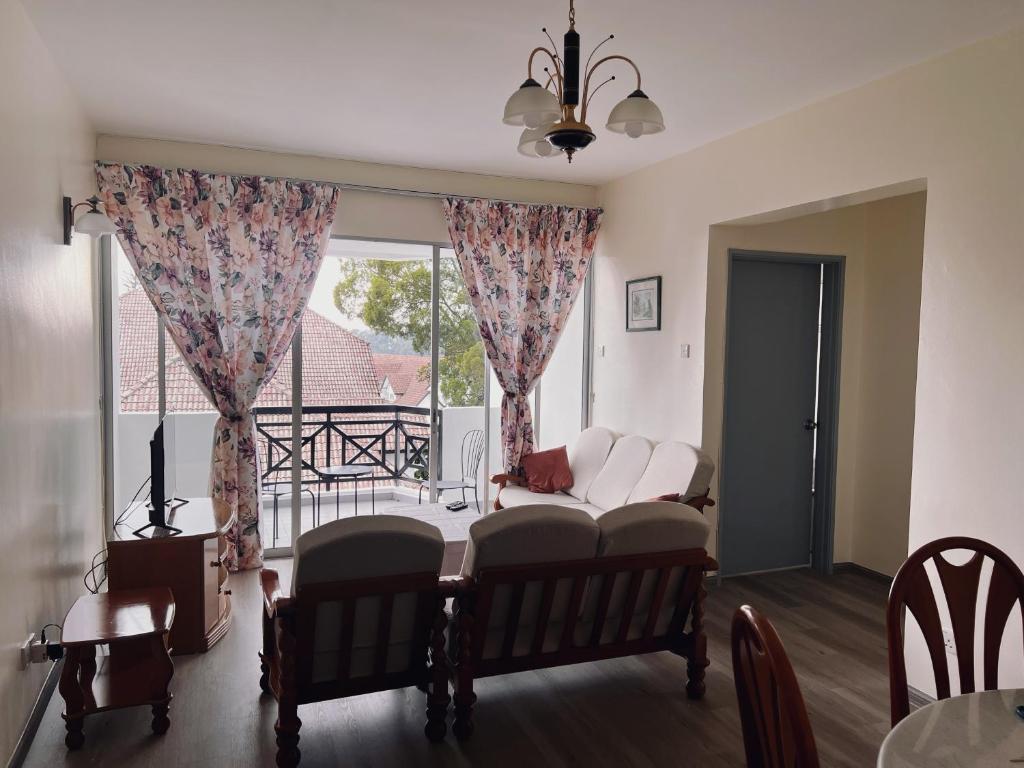 a living room with a couch and a large window at Blossom Silverpark Apartment in Bukit Fraser