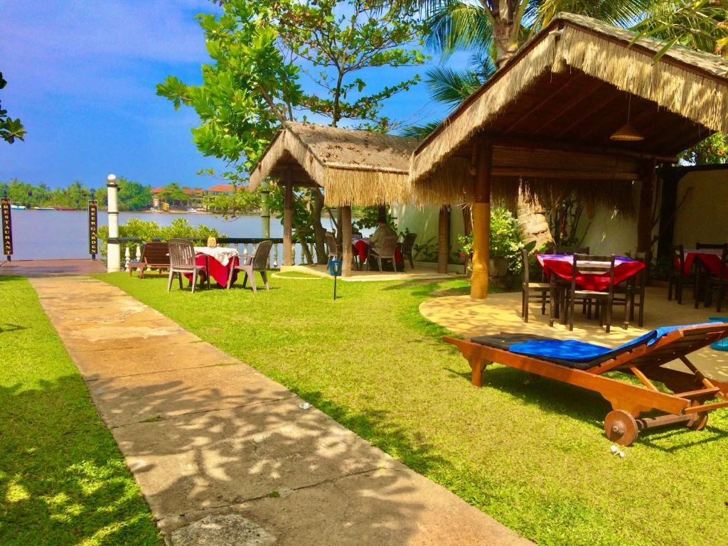 un patio trasero con una mesa y sillas y un pabellón en Hotel Hemadan, en Bentota