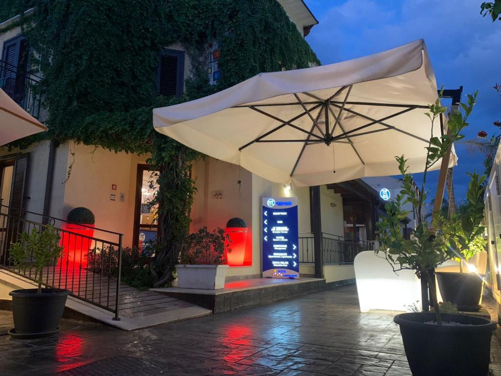 a white umbrella sitting outside of a building at Residence Hotel Marino Tourist in San Vito lo Capo
