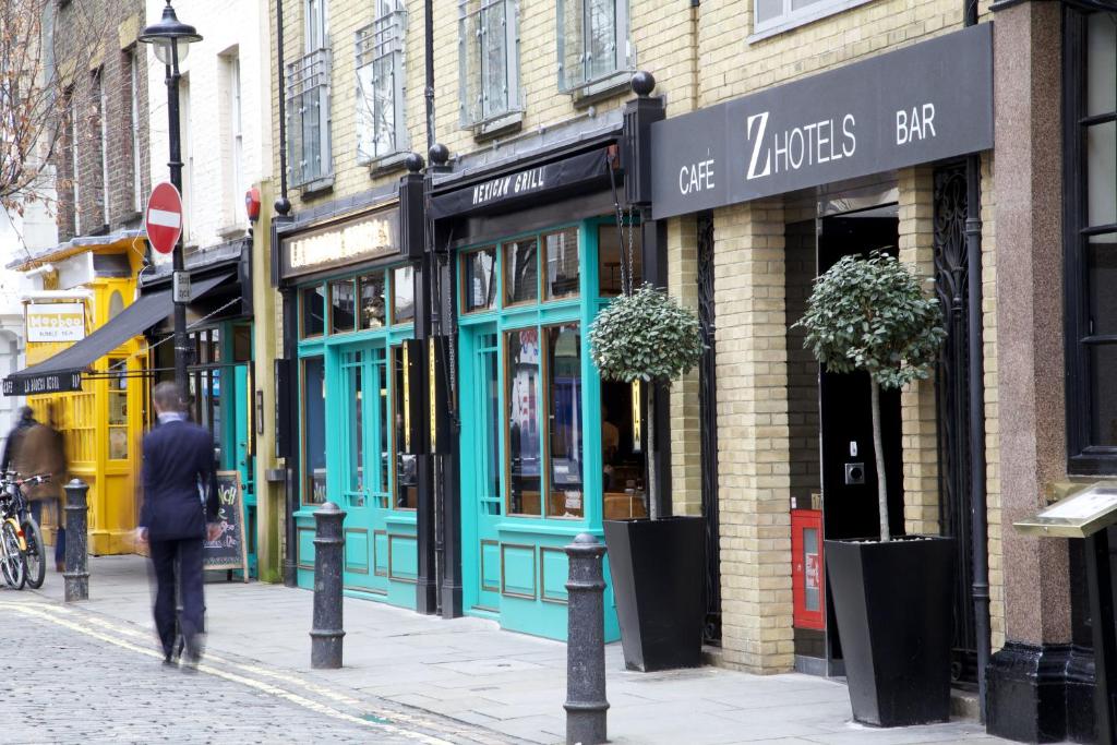 un hombre caminando por una calle frente a una tienda en The Z Hotel Soho en Londres