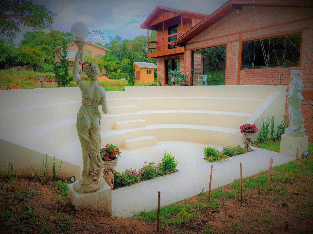 a statue of a woman standing in a garden at Recanto da Paz - Aos pés do Morro da Borússia in Osório
