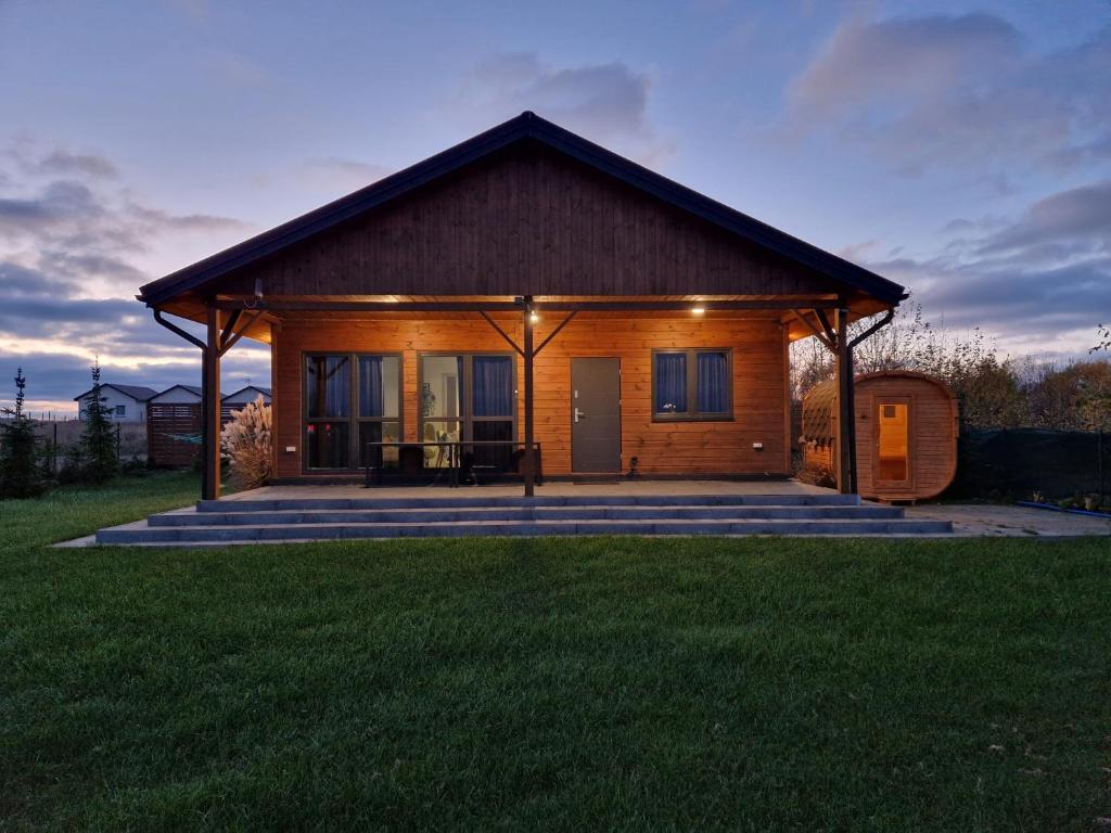 a log cabin with a porch and a grass field at Gąski Baltic Lark Dom 100m2 3 sypialnie 2 łazienki Sauna Prywatny teren in Gąski