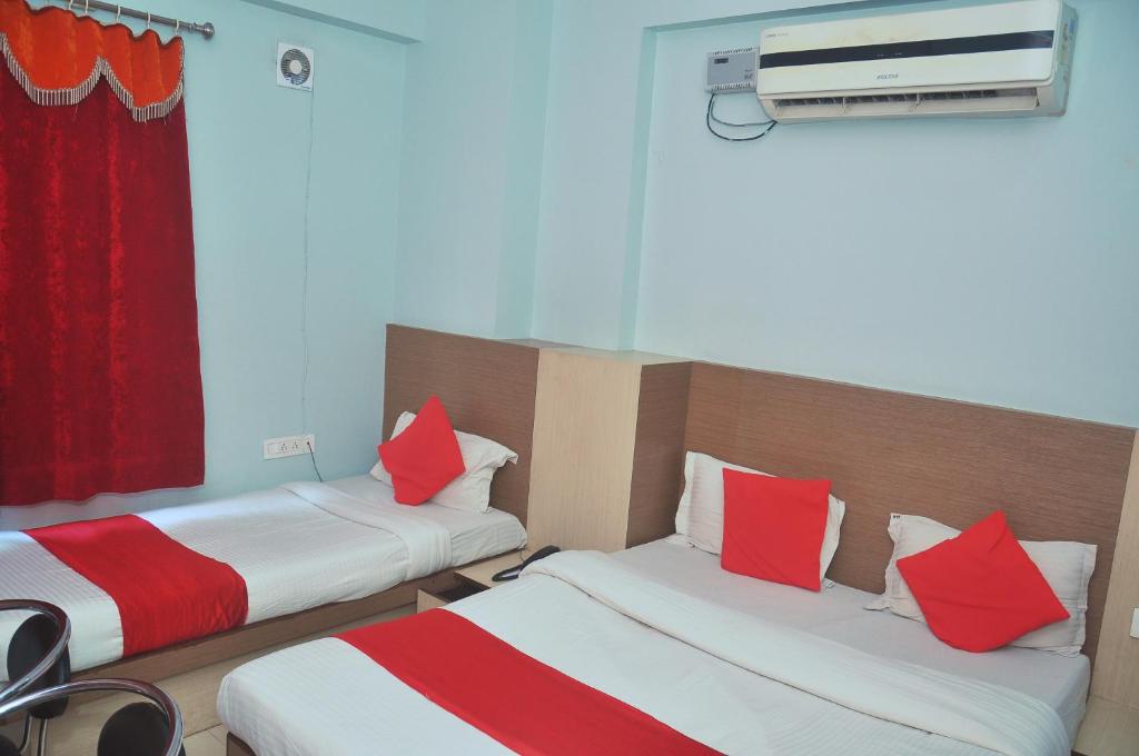 um quarto com 2 camas com almofadas vermelhas e brancas em Hotel Thikana Palace em Jaipur