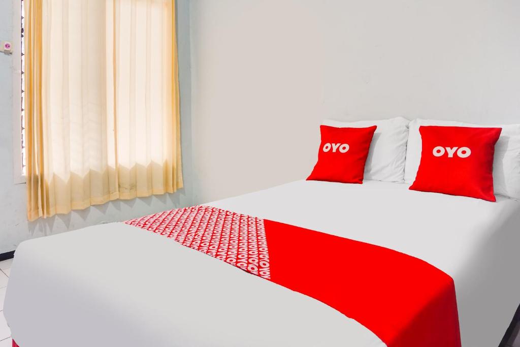 a bedroom with two red pillows on a bed at OYO 91926 Serayu Sumbersari Homestay in Jenggrik