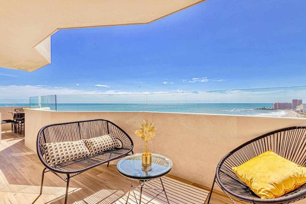 un balcón con 2 sillas, una mesa y el océano en 797 Holiday Rentals - Benalbeach- Moderno piso para 5 con vistas al mar, en Benalmádena