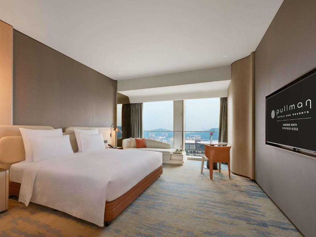 a hotel room with a bed and a flat screen tv at Pullman Shenzhen North in Shenzhen